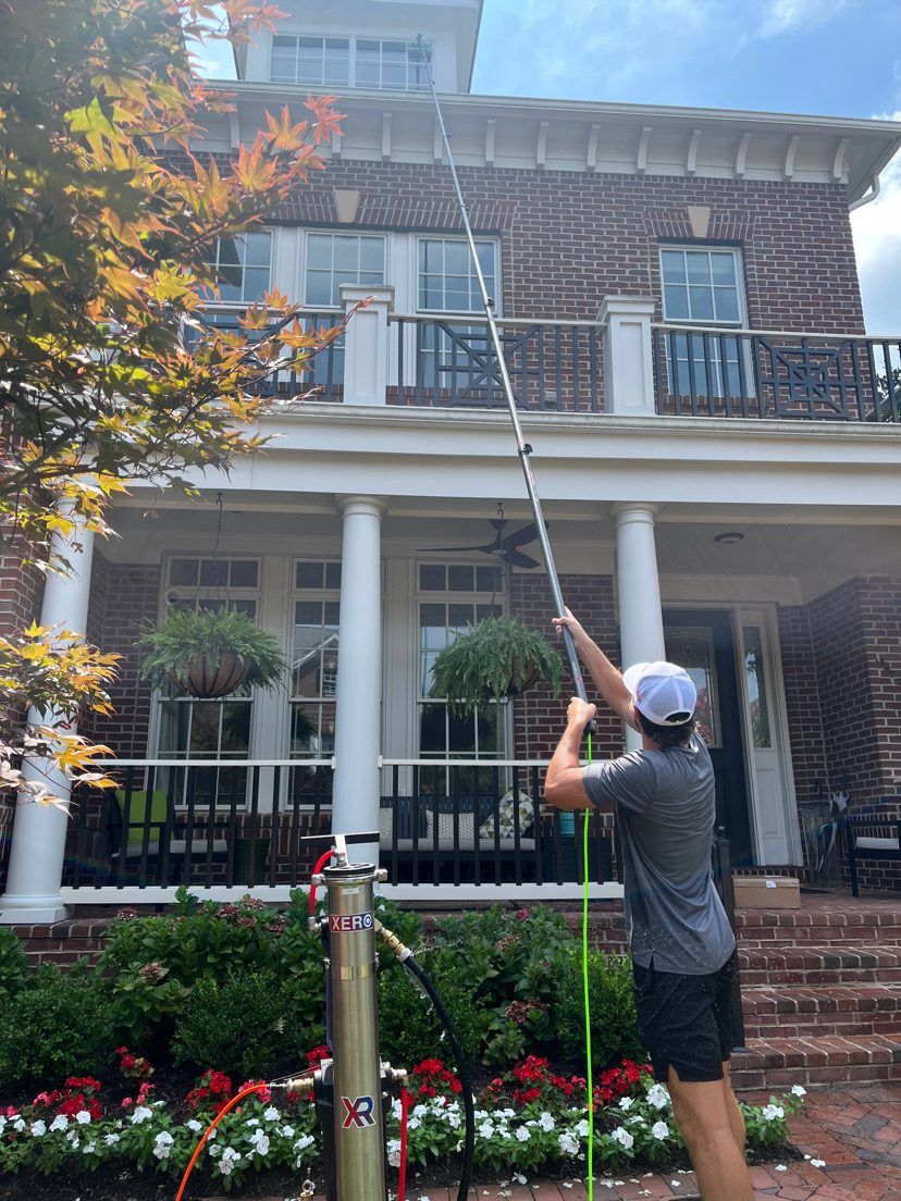 Window cleaning technician using a pure water pole on a two-story home in Bethesda, MD
