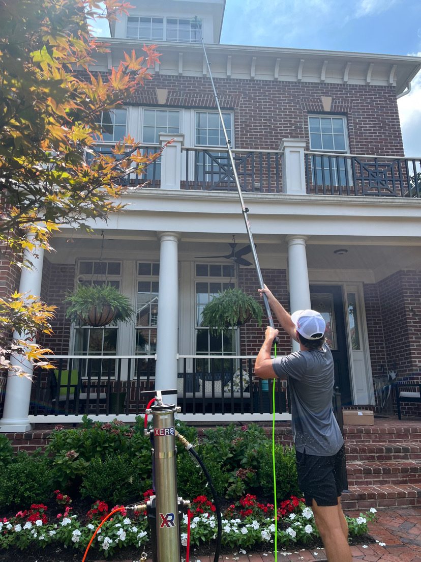 TD Home Solutions cleaning upper-story windows with a pure-water pole on a brick home